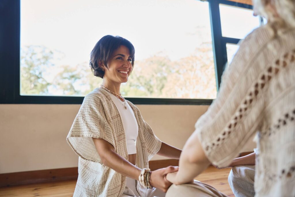 happy-yoga-coach-holding-hands-of-woman-during-gro-2026-01-08-00-17-08-utc.jpg